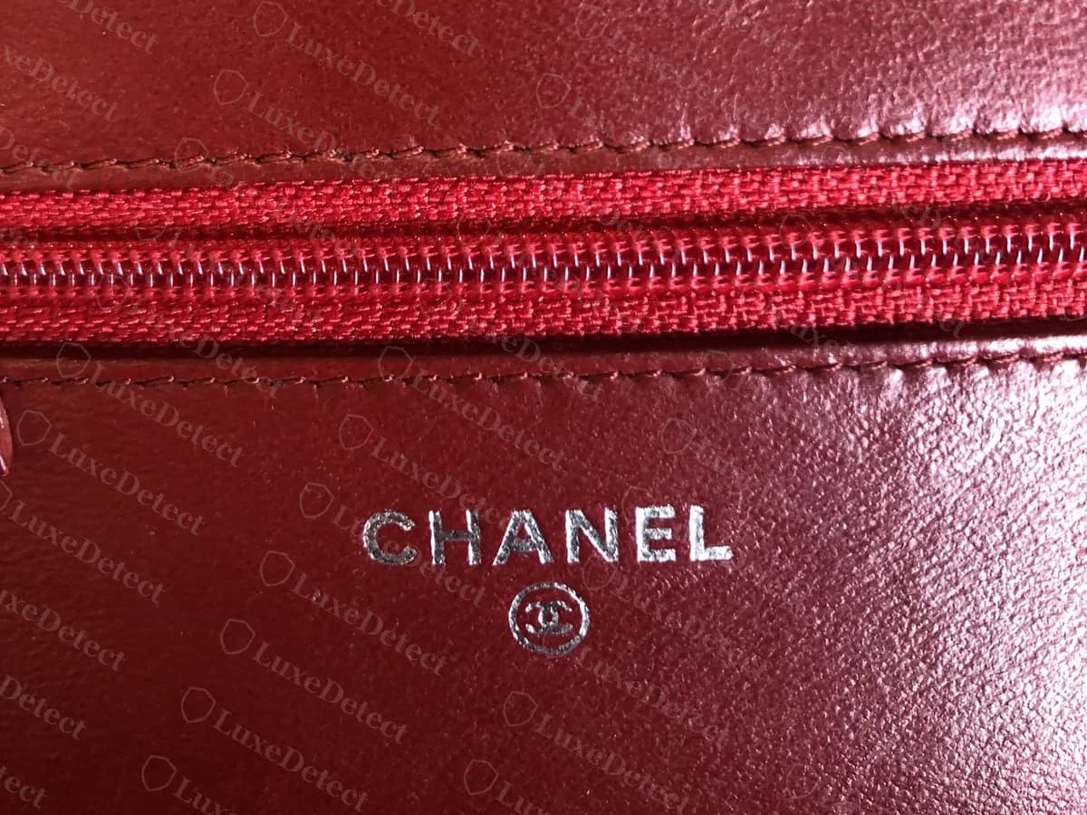 Genuine Chanel WOC interior stamp in silver foil on red leather, CHANEL above a circled CC, with a red zip above it