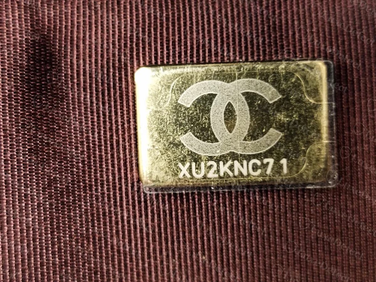 Genuine Chanel WOC interior serial plate: a gold rectangular plate in the burgundy lining showing a CC logo above the code XU2KNC71