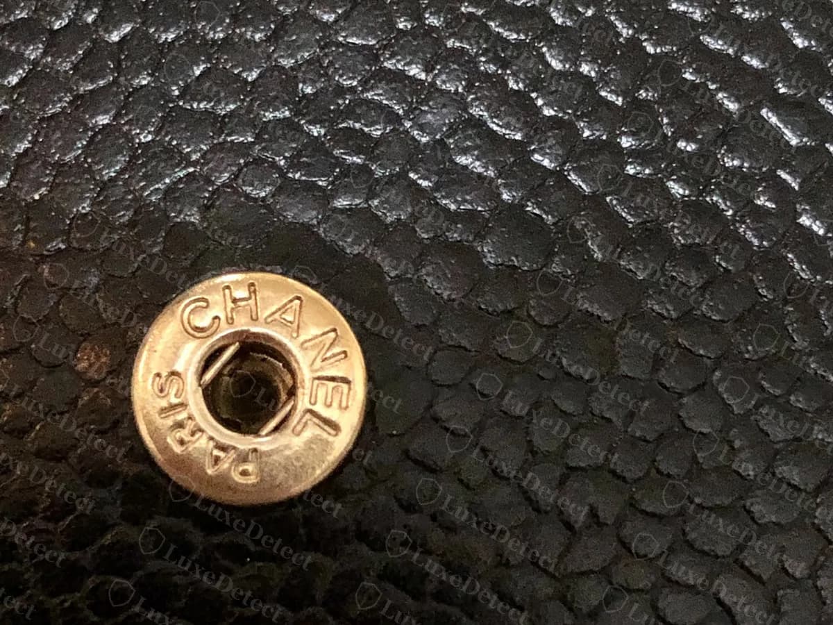 Genuine Chanel WOC flap snap on black caviar: a gold-tone stud with CHANEL and PARIS engraved around its rim