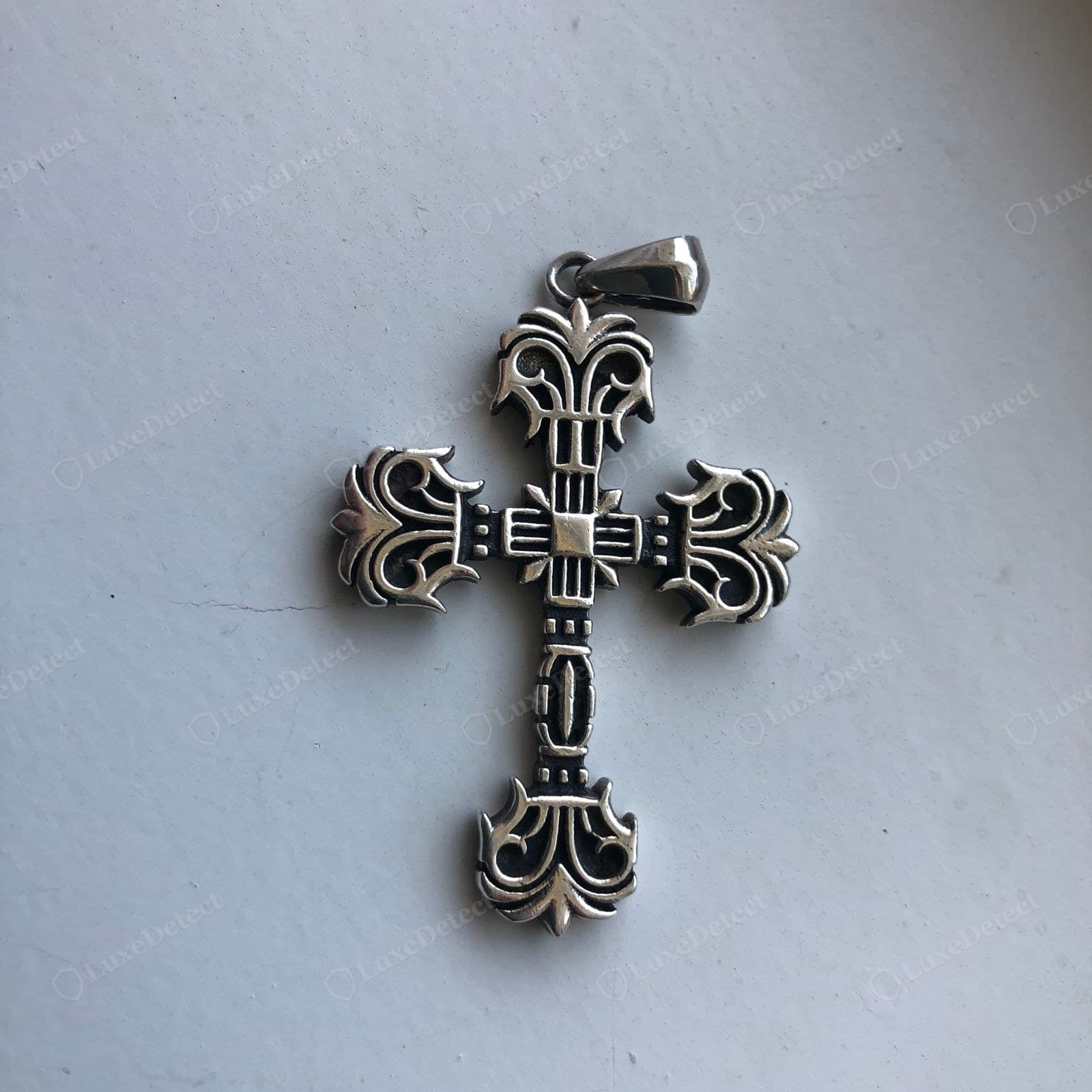 Genuine Chrome Hearts cross — a fleur-de-lis cross pendant, crisply cast with clean 3D definition, deep oxidised recesses and hand-finished high points, a smooth clean bail