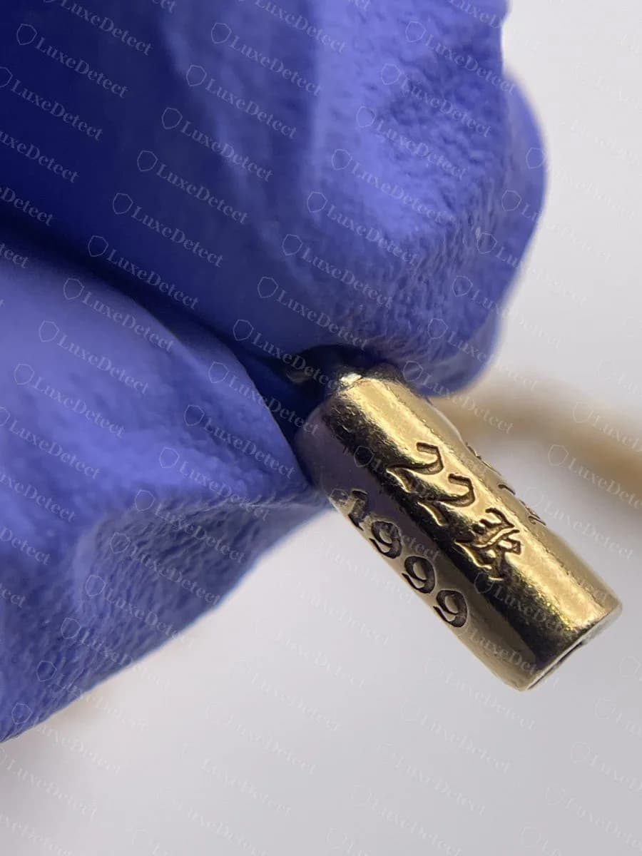 Original: el cilindro del cierre de una pulsera de cruz genuina de oro de 22k de Chrome Hearts, con el sello "22K" y debajo el año "1999", en caracteres nítidos y golpeados con uniformidad