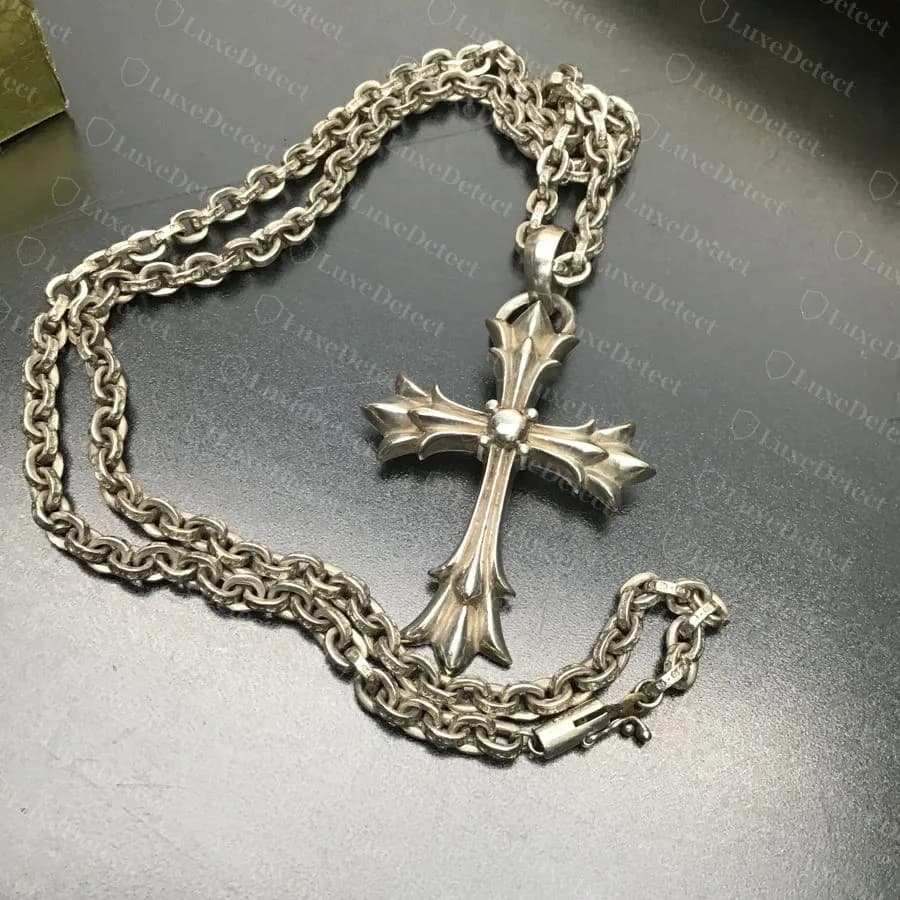Original: un colgante de cruz mediano genuino de Chrome Hearts en una cadena paper chain, con los eslabones ovalados aplanados parejos en toda la longitud y la cruz limpiamente fundida