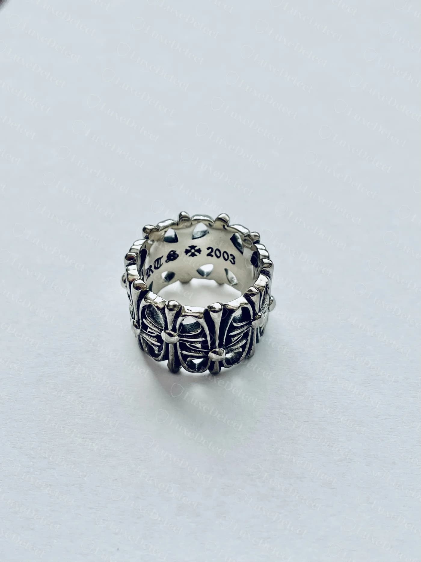 Genuine Chrome Hearts cross-motif ring, the cross cutwork motifs repeating evenly around the exterior band with consistent depth and spacing, interior stamp reading a year and maker's cross visible through the band opening