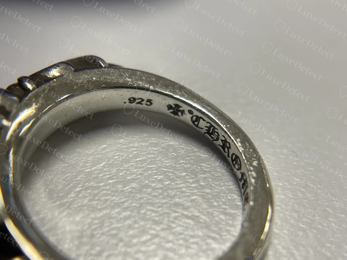 Genuine Chrome Hearts ring interior stamp reading ".925" then a small maker's cross then "CHRO..." in blackletter, struck deep with dark oxidised fill in the letter recesses