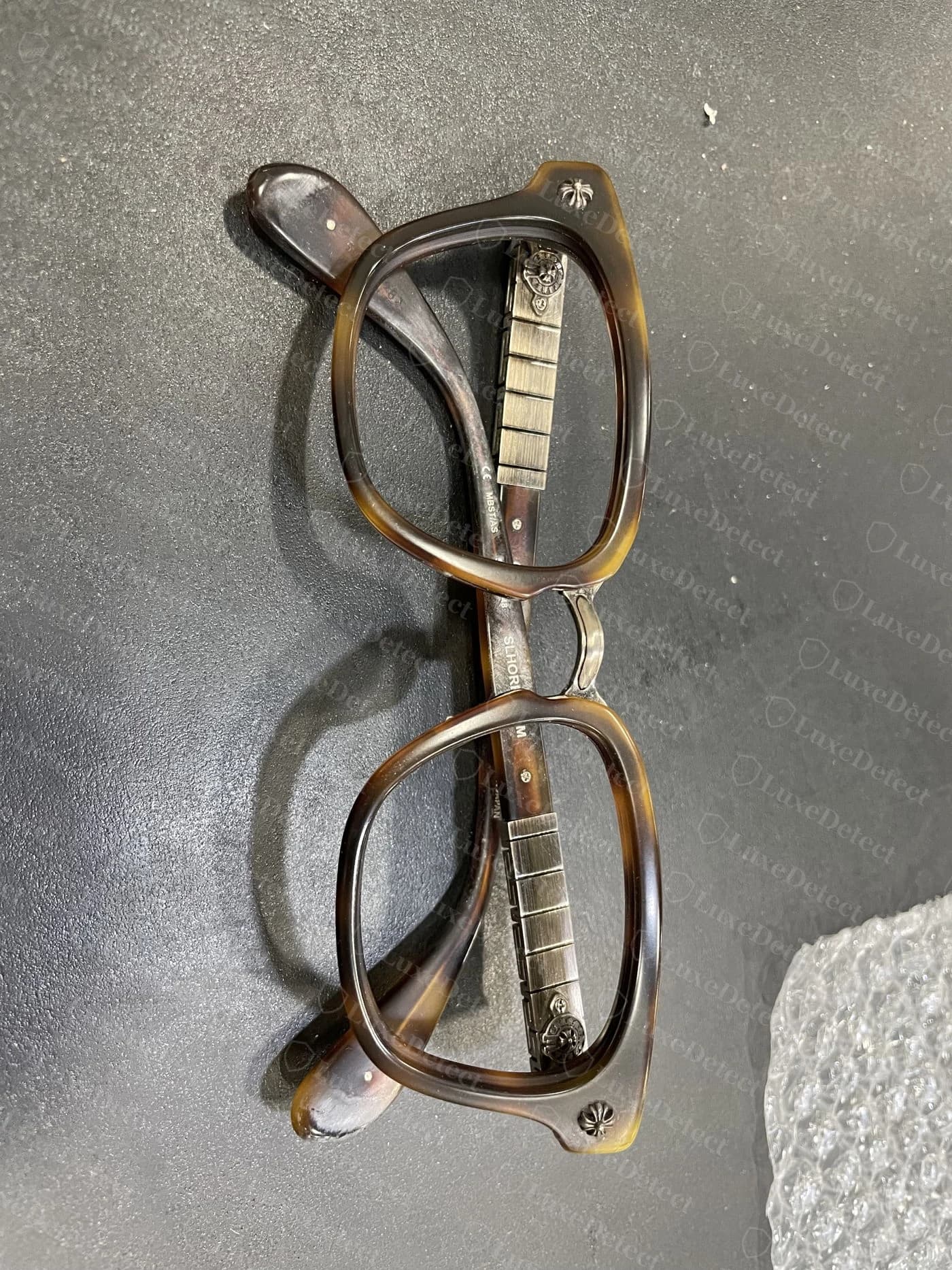 Genuine Chrome Hearts eyewear hinge hardware — crisp cross-hatched temple panel with a cast floral cross medallion