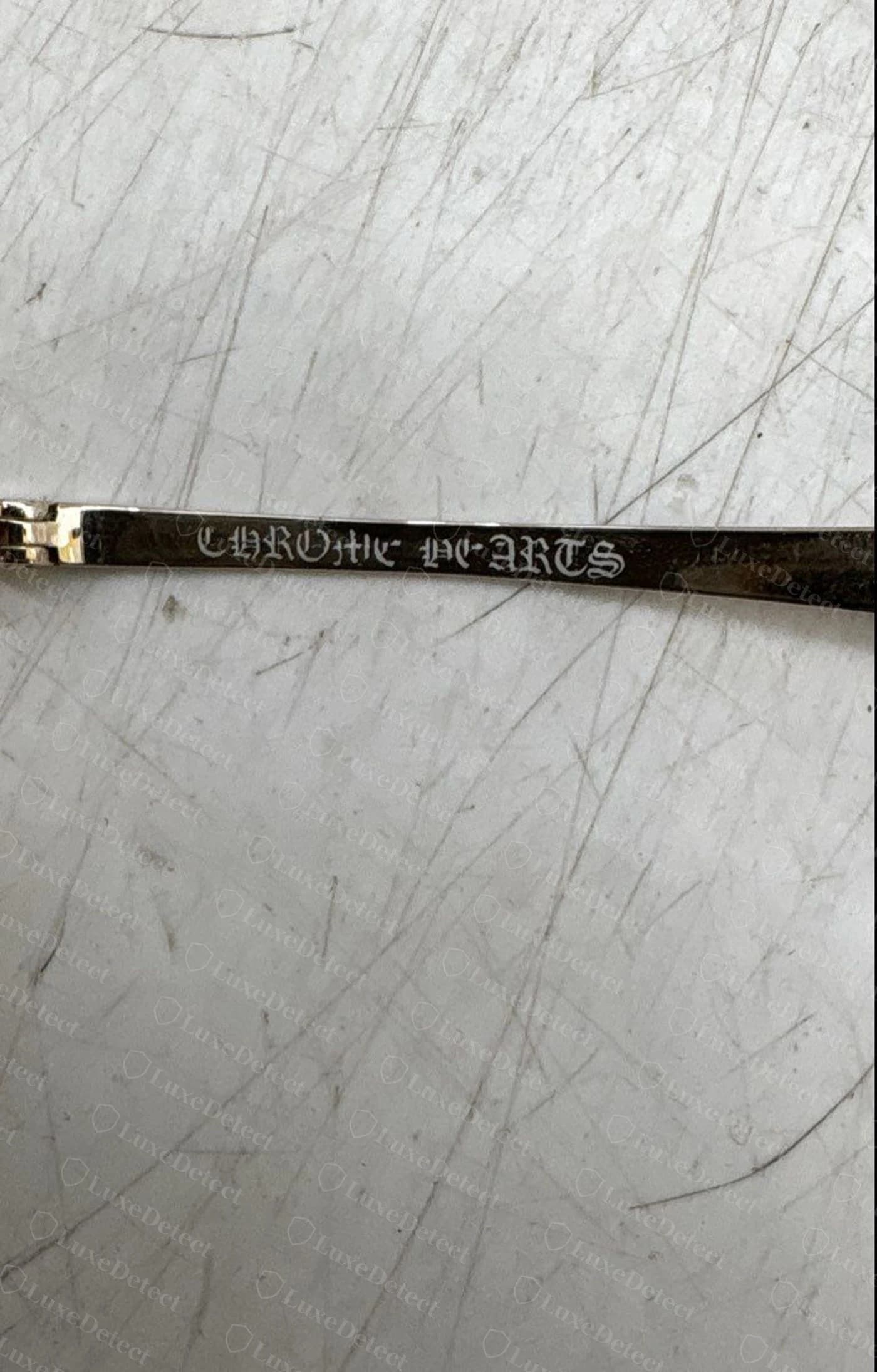 Counterfeit Chrome Hearts sunglasses temple — the wordmark reads as a garbled, misspelled mess instead of CHROME HEARTS