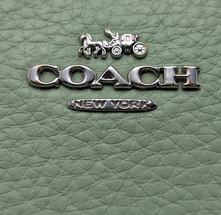 Cartera Coach moderna con cremallera: caballo y carruaje, COACH y una placa NEW YORK en metal pulido sobre piel de grano pebbled