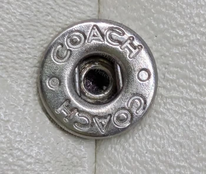 Cartera Coach antigua: botón del broche con COACH escrito alrededor del borde, con espaciado uniforme y bordes limpios