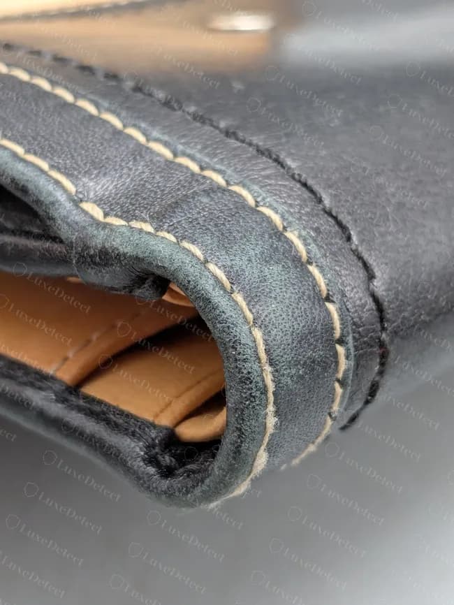Billetera Coach antigua: costura de contraste uniforme siguiendo un borde doblado, con desgaste natural en el pliegue