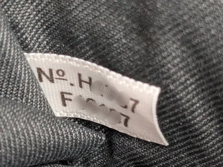 Modern Coach keychain wallet: white No. tag with two lines, a code and a style number (middle digits blurred)