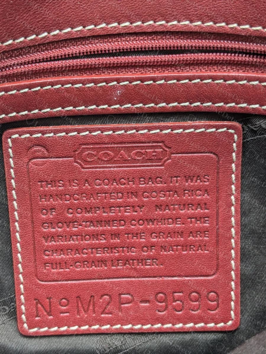 Una targhetta creed Coach originale in pelle rossa con la scritta handcrafted in Costa Rica e sotto il codice con lettere N°M2P-9599: dicembre 2002, lettera dello stabilimento P, stile 9599