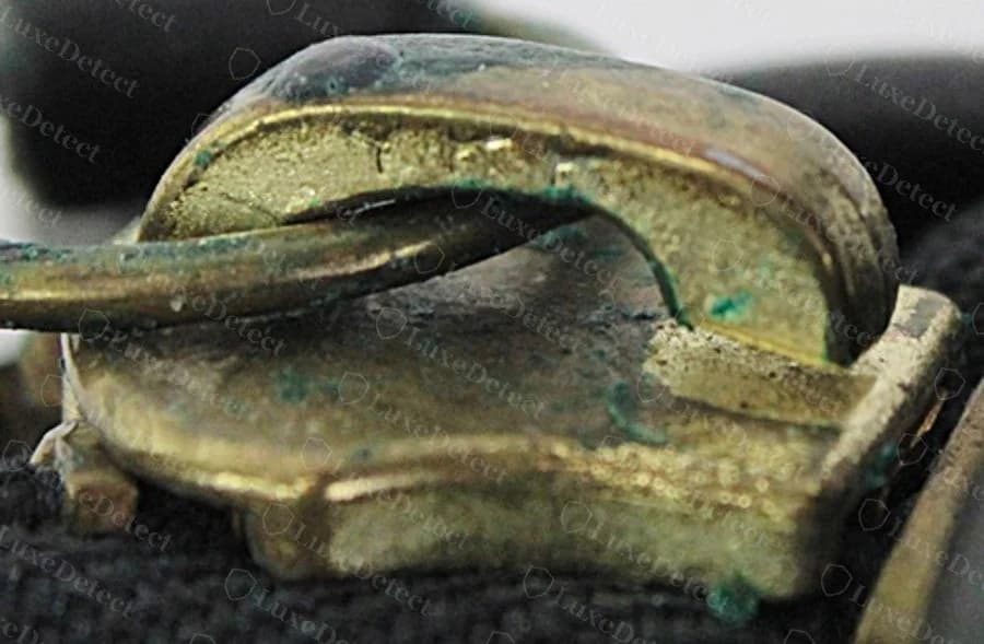 Counterfeit Legacy turn-lock hardware: soft, rounded casting edges and premature greenish tarnish spotting across the surface.