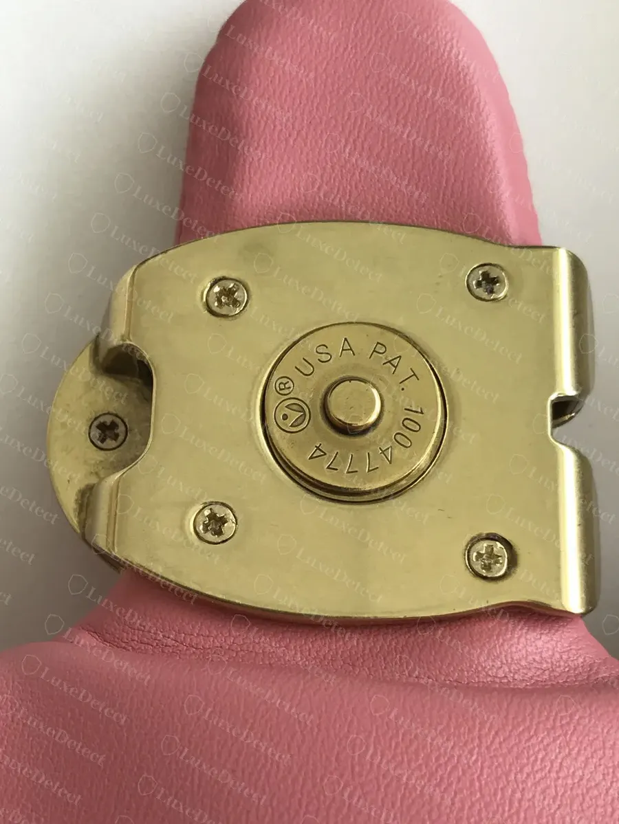 Back of the turnlock on a verified authentic Pillow Tabby: a smooth brass backplate, four screws and a centre disc engraved "USA PAT." with a patent number.
