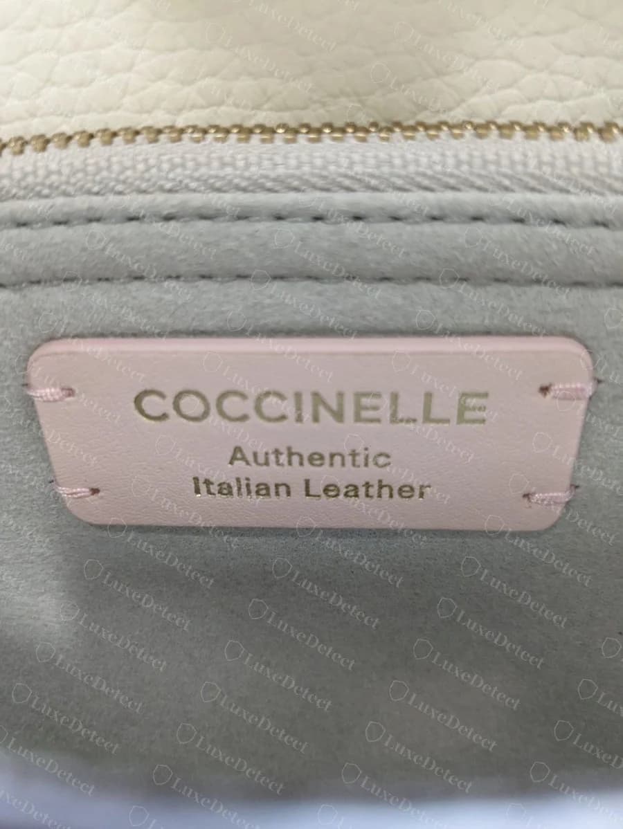 Parche de piel rosa original de Coccinelle estampado en dorado con COCCINELLE, Authentic Italian Leather, cosido con hilo rosa a un forro gris