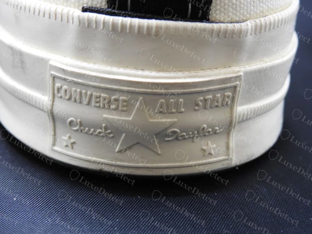 Echte eingeformte Fersenplatte eines CDG PLAY x Converse Chuck 70 mit CONVERSE ALL STAR und Chuck Taylor in Schreibschrift zu beiden Seiten eines großen Sterns, über einem schwarzen Fersenstreifen