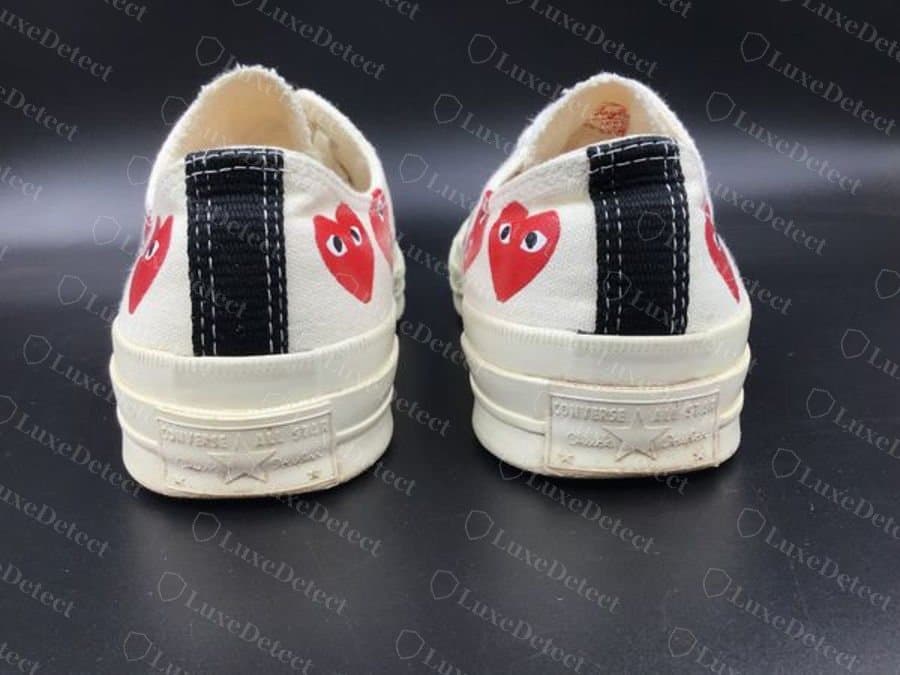 Comme des Garçons Play x Chuck 70 Ox autentica, vista posteriore: la striscia nera del tallone, l’intersuola egret e la placca del tallone Converse All Star in rilievo