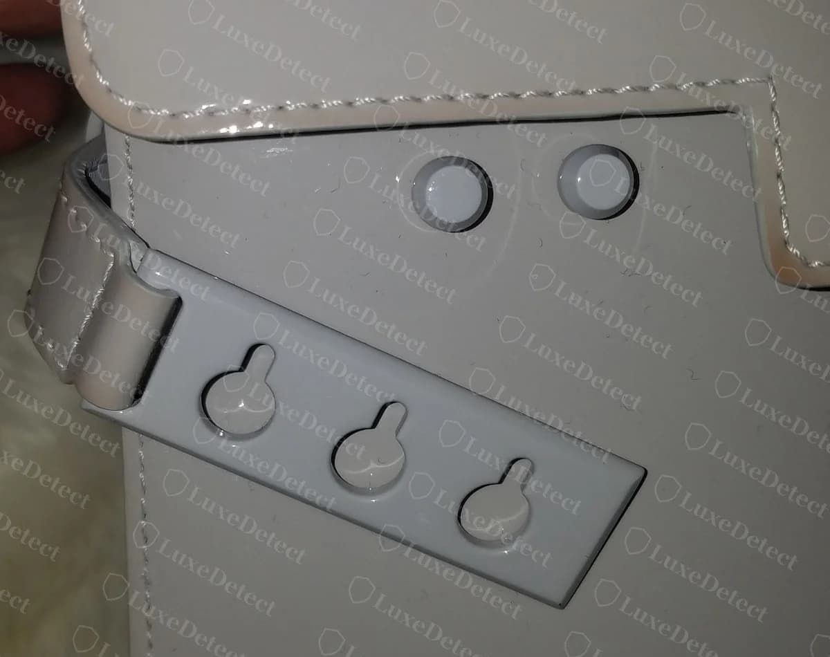 Counterfeit grey patent Delvaux Tempête with the side plate and both studs coated in grey to match the leather, instead of bare metal