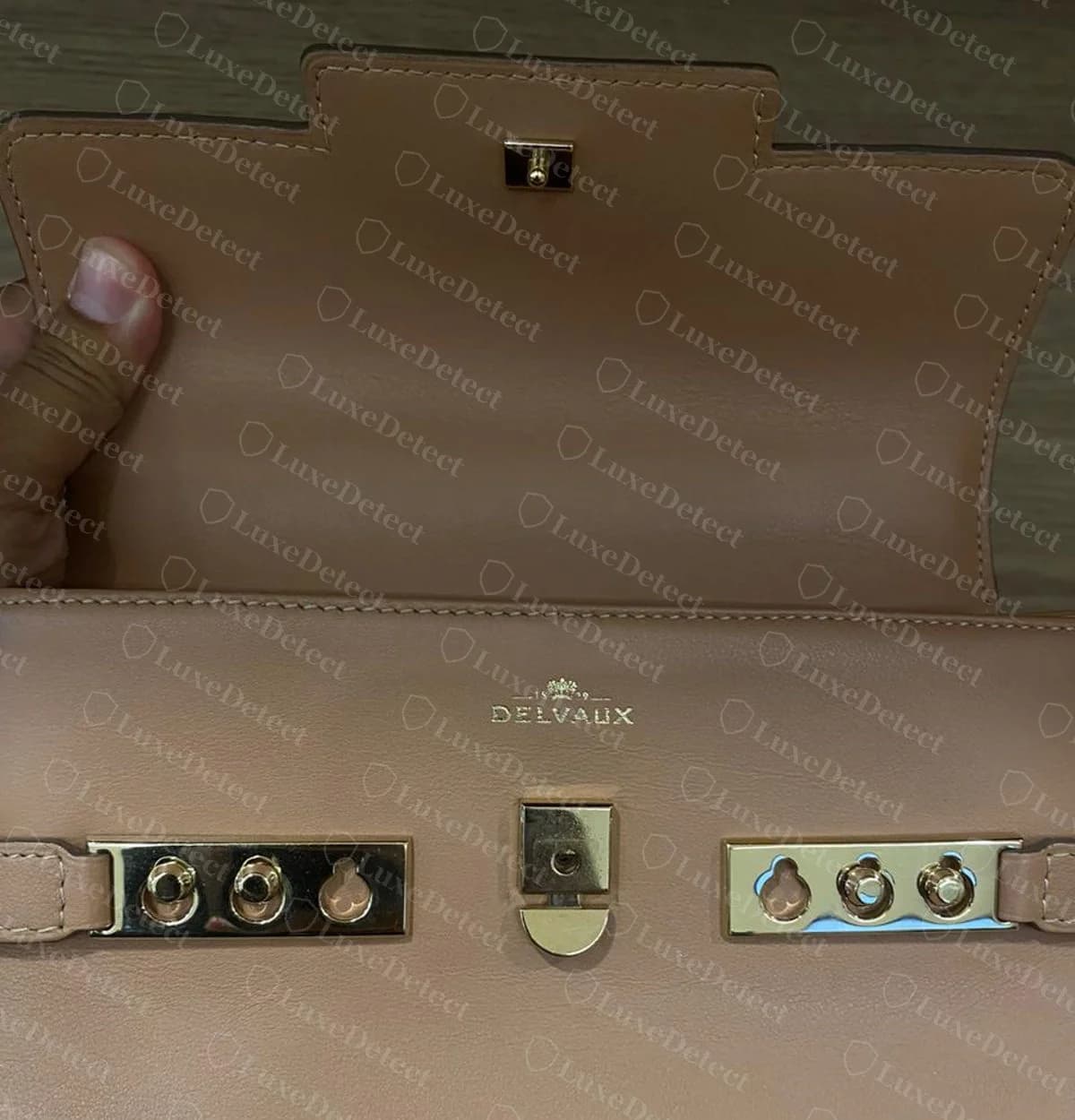 Genuine Delvaux Tempête with the flap open, showing the DELVAUX stamp, the central lock plate and both side plates with two studs seated in each
