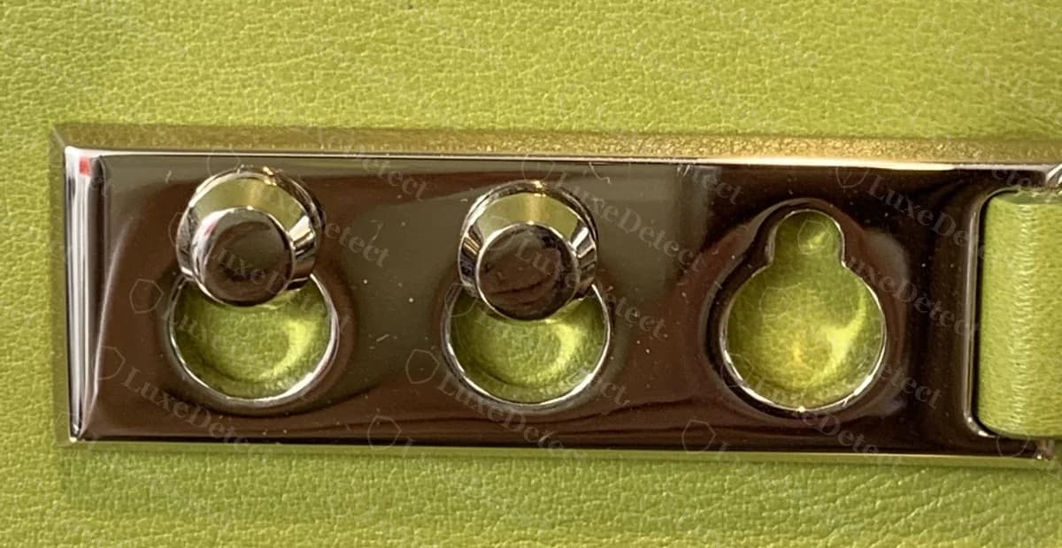 Genuine Delvaux Tempête side plate in silver tone with two stud heads seated in the keyhole openings and the third opening empty, on lime leather