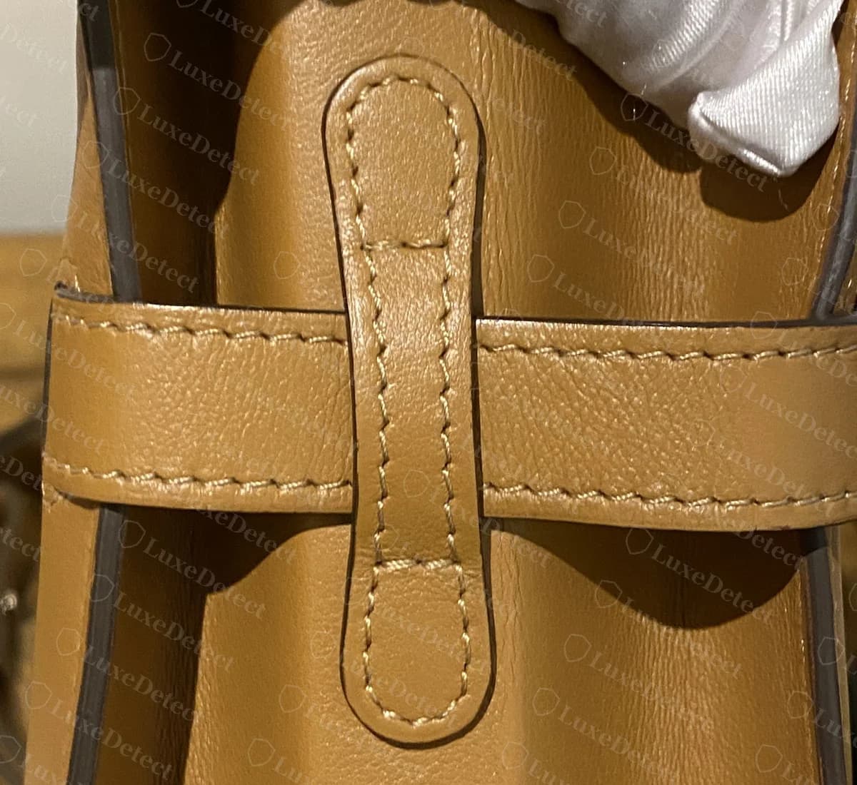 Genuine Delvaux Tempête side view with the horizontal leather strap passing under a vertical stitched loop on the side panel