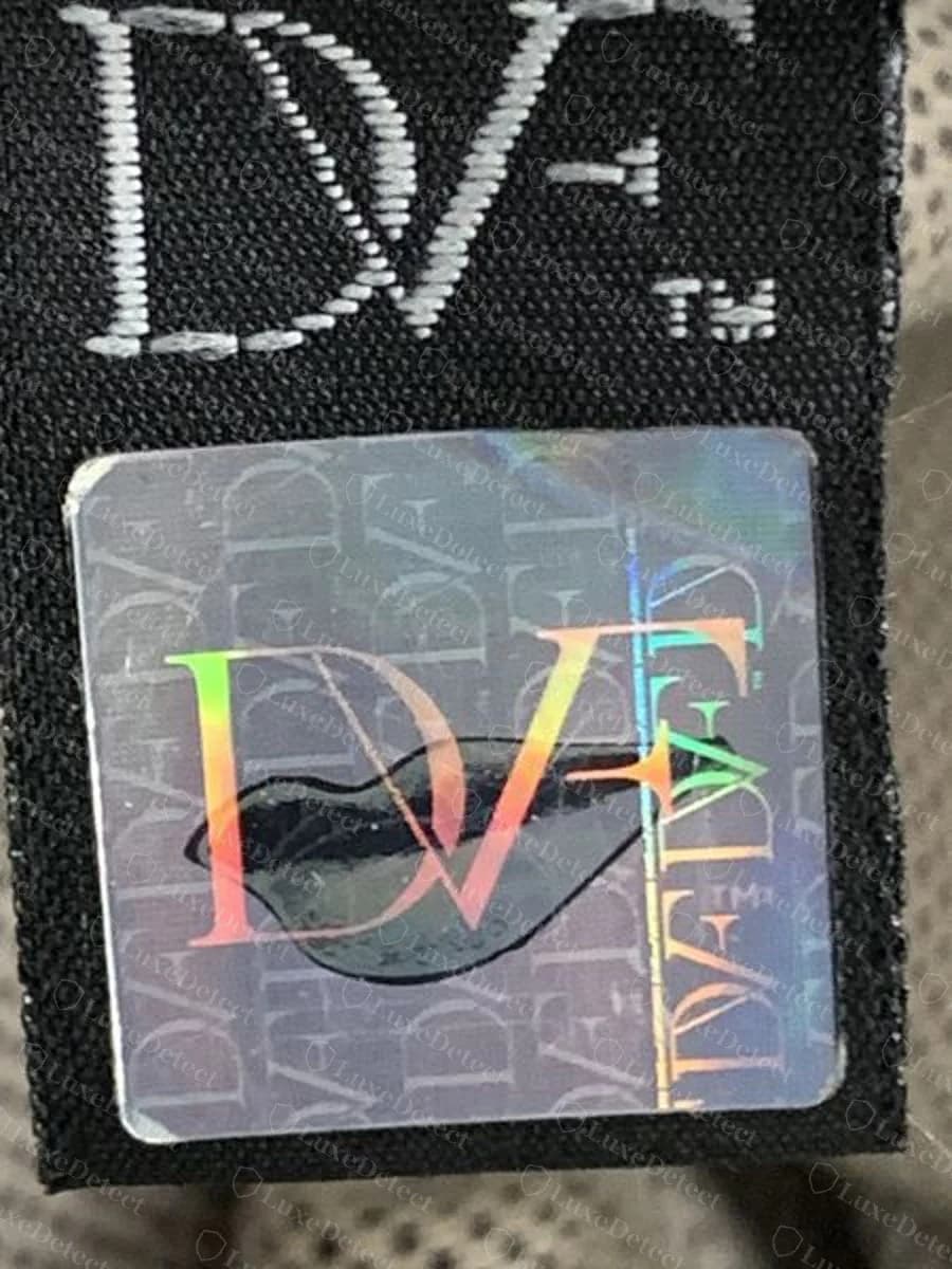 Etiqueta tecida preta Diane von Furstenberg original com DVF e sinal de marca registrada e um adesivo holográfico em formato de lábios, costurada no forro de uma tote de couro caramelo
