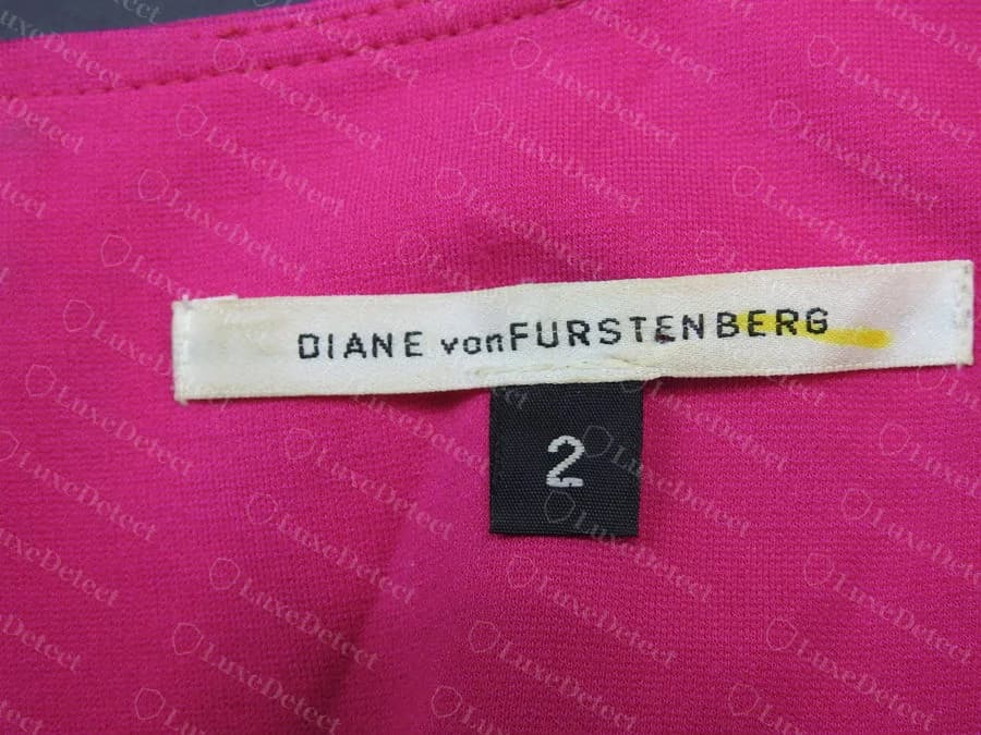 Etiqueta blanca tejida de cuello original de Diane von Furstenberg con el texto DIANE von FURSTENBERG y una etiqueta negra de talla aparte con el número 2, cosida en un vestido rosa