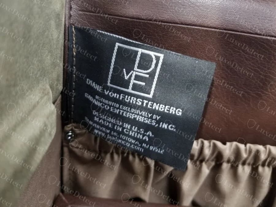 Etiqueta tecida preta Diane von Furstenberg original com um monograma D v F em caixa, com os dizeres Distributed exclusively by Badanco Enterprises, Designed in U.S.A., Made in China, dentro de um baú de cosméticos