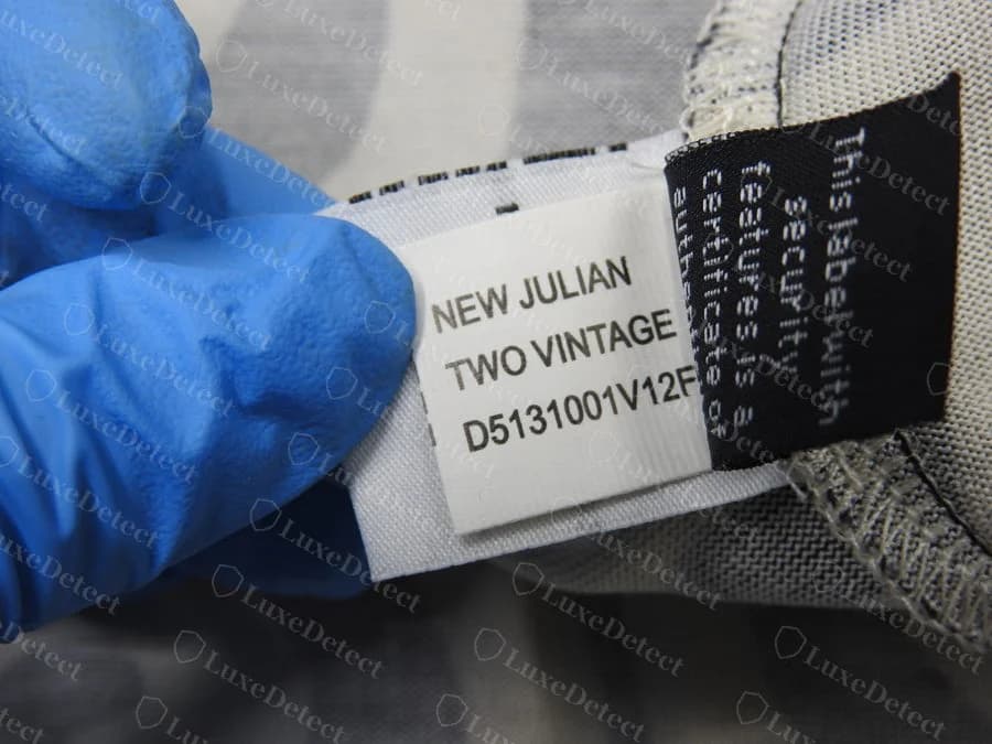Etiqueta de estilo tecida branca Diane von Furstenberg original com NEW JULIAN TWO VINTAGE e um código começando por D5131001, costurada ao lado de uma etiqueta de segurança preta