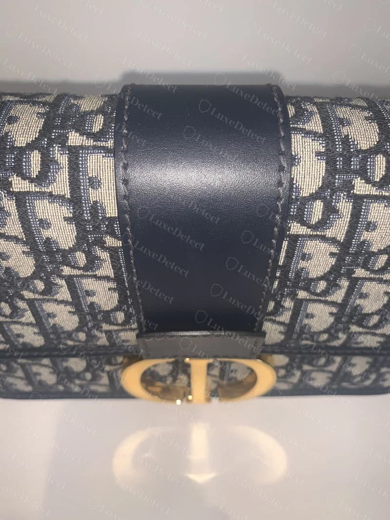 Genuine CD turn-lock clasp on an oblique jacquard 30 Montaigne flap bag, showing the evenly polished gold hardware and the strap tab stitched above it