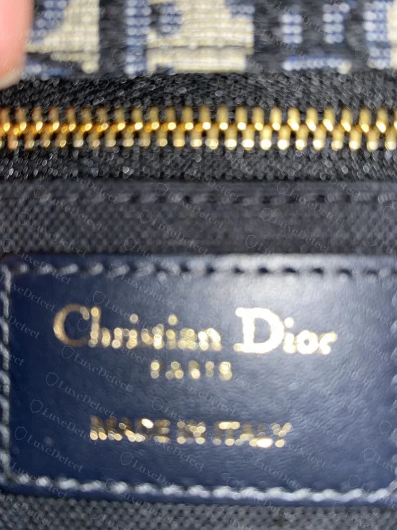 Genuine interior leather tag reading "Christian Dior Paris" and "Made in Italy" in gold foil, stitched flush into the lining seam