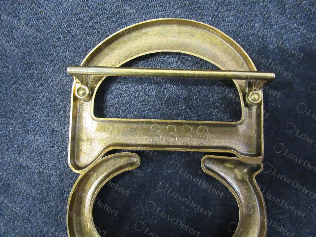 Counterfeit CD buckle reverse, a rough cast back with a cast-in number "3339", uneven thickness, visible tool marks and pitted, dull plating