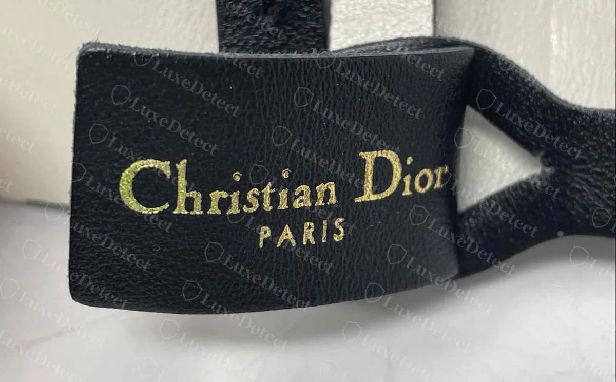 Genuine Dior belt inner tab, "Christian Dior PARIS" in bright gold foil, evenly filled letters with the house serif and widely spaced PARIS