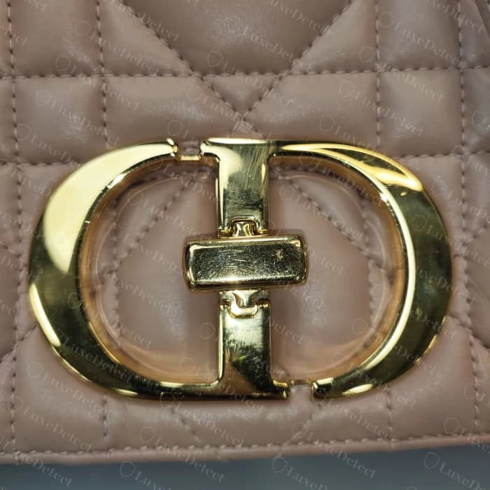 Close-up of a genuine Caro CD turn-lock clasp on macrocannage leather, showing the fused oval outline and rectangular locking bar