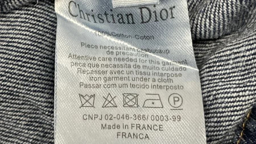 Chaqueta de mezclilla Dior falsa con la etiqueta de cuidados recortada: Christian Dior, 100% Cotton-Coton, texto de cuidados, CNPJ y Made in France, sin código de estilo ni número