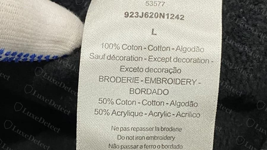 Étiquette d'un pull Dior authentique : 100% cotton hors décoration, broderie indiquée 50% cotton et 50% acrylic, avec une ligne no-iron-embroidery