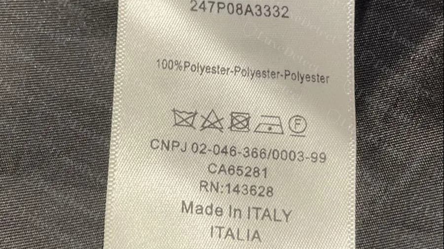 Pieza Dior original con números de importación de EE. UU.: línea CNPJ, CA65281, RN:143628 y Made in Italy debajo de la composición y los símbolos de cuidado