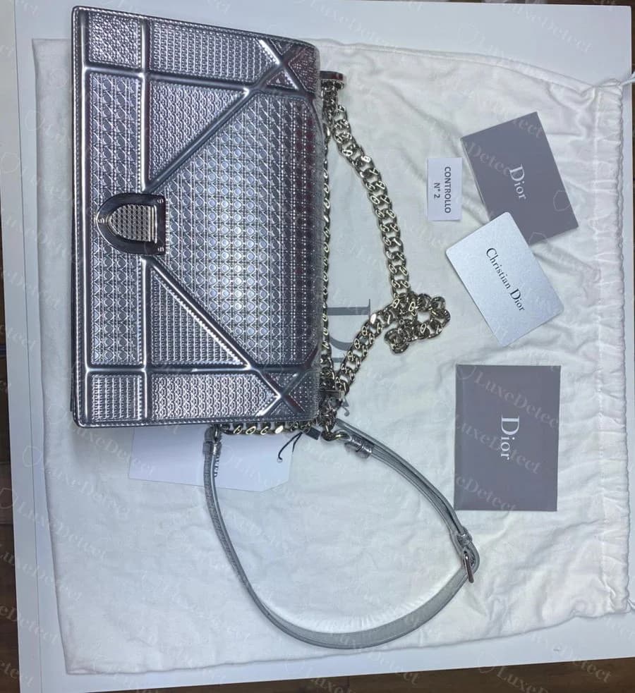 Metallic Dior Diorama bag laid flat with its dust bag, shoulder chain, and a full accessory set: a Christian Dior authenticity card, a numbered control ticket, and branded paper inserts