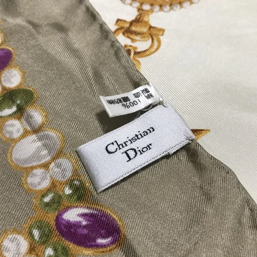 Authentic Dior silk scarf detail: sewn woven label and crisp printed motif edges with consistent color, on a genuine jewelry-print silk twill