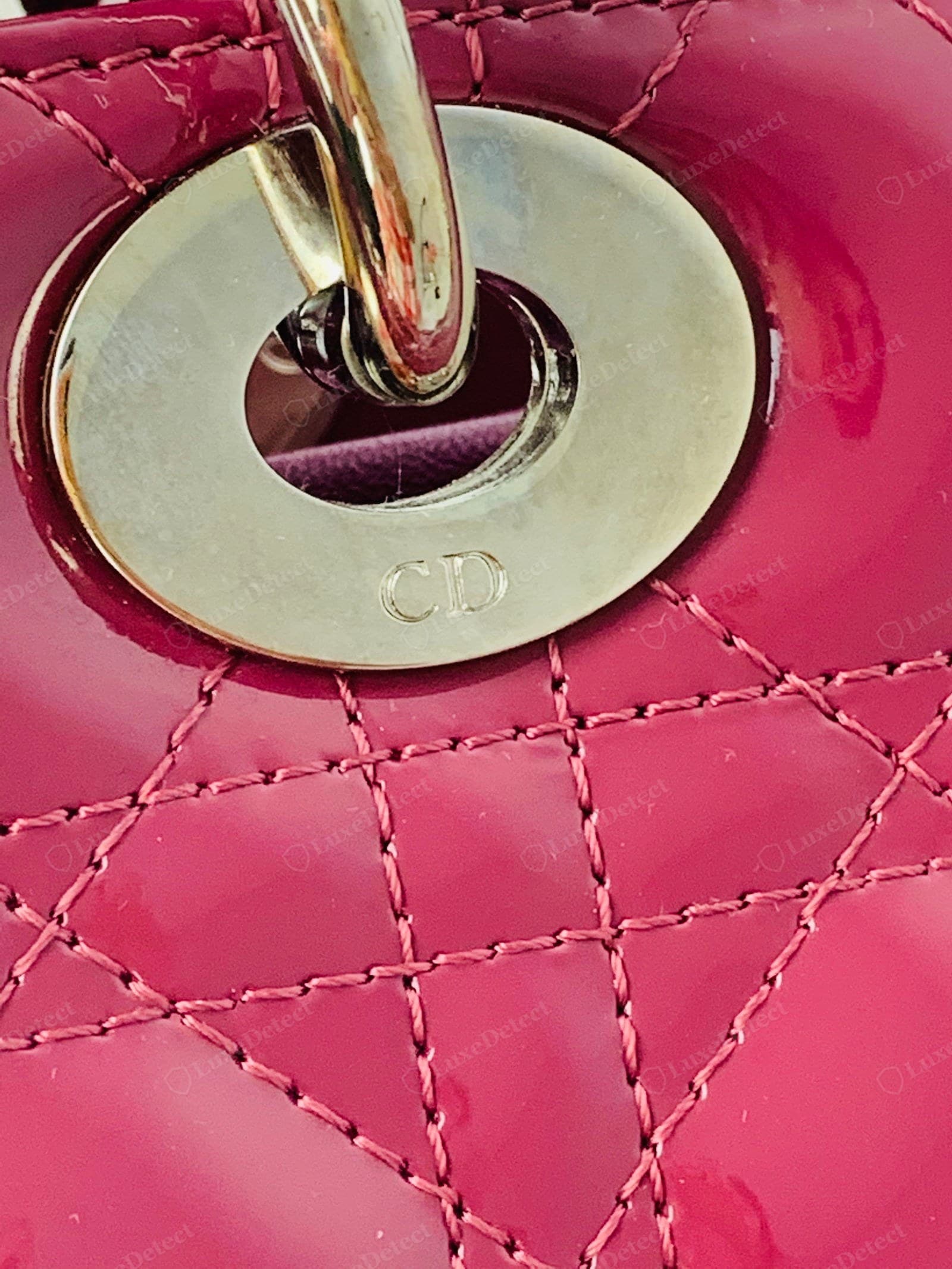 Genuine Lady Dior cannage — black lambskin with an even, plump quilt: uniform diamonds, straight matched stitch lines, a firm rounded fill, and the polished "CD"-engraved ring at the handle attachment