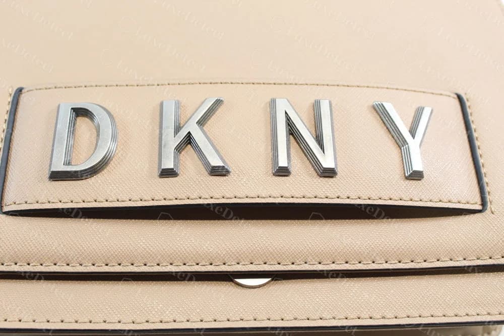 Genuine DKNY beige saffiano leather bag with four separate silver-tone block letters D K N Y mounted on a stitched leather panel