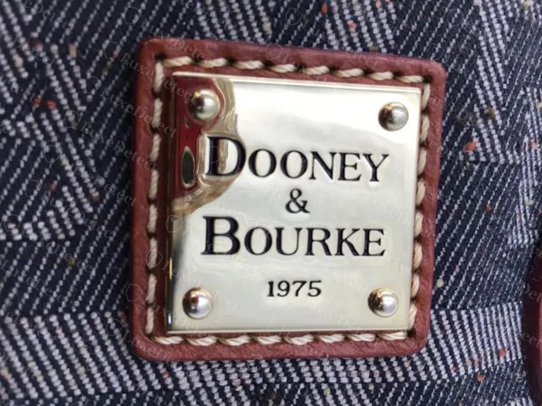 Placa original: una placa cuadrada DOONEY & BOURKE 1975 con cuatro remaches sobre un soporte de piel cosido