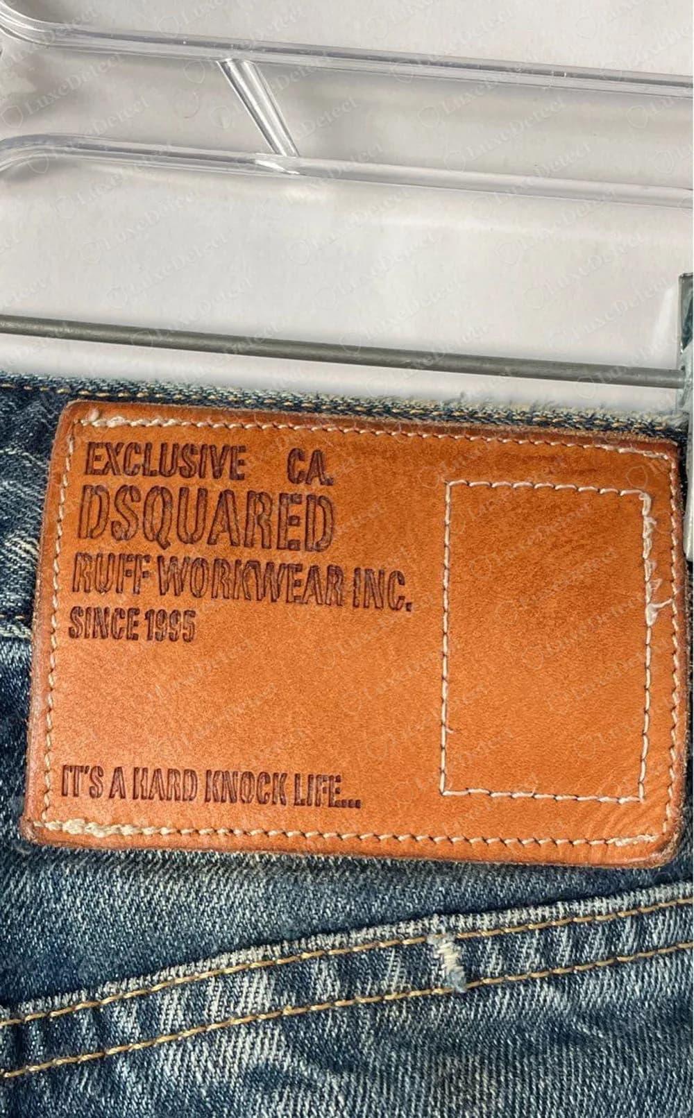 Genuine older Dsquared2 jeans: tan leather back patch stamped EXCLUSIVE CA. DSQUARED RUFF WORKWEAR INC. SINCE 1995 and IT'S A HARD KNOCK LIFE, with a stitched empty rectangle at its right