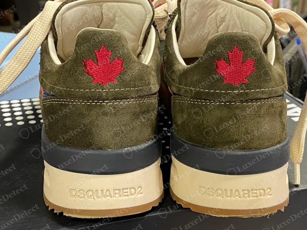 Genuine Dsquared2 Original Legend sneakers in olive suede seen from behind, with an embroidered red maple leaf on each heel tab and DSQUARED2 moulded into the cream heel of each sole