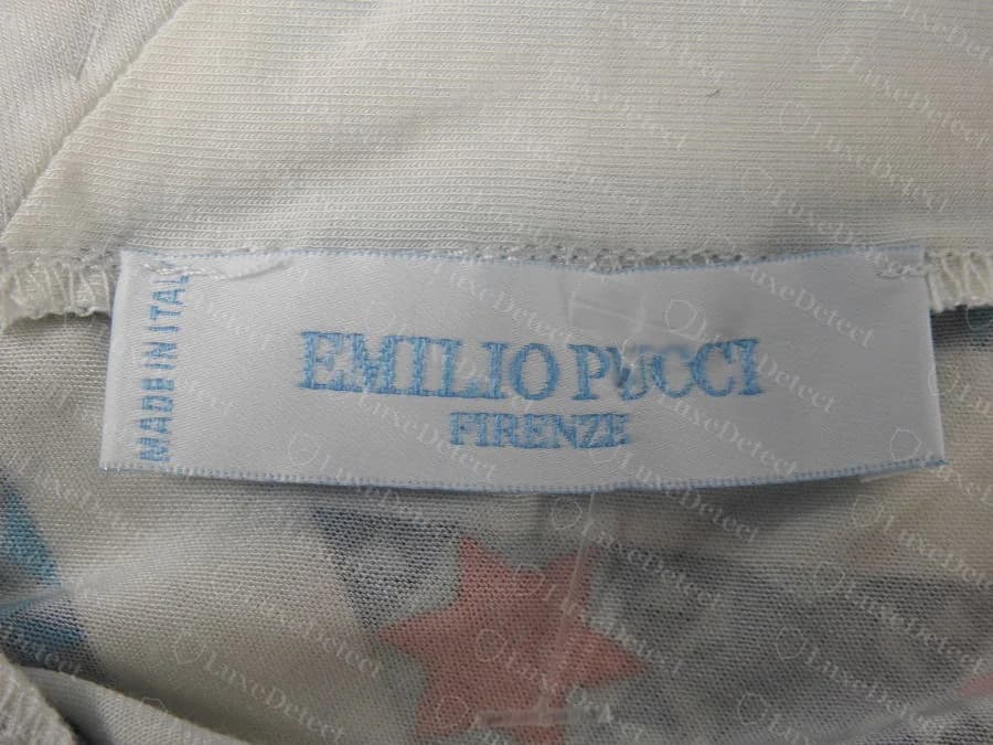 Etiqueta tejida de cuello Emilio Pucci original, con letras azul claro sobre blanco que dicen "EMILIO PUCCI FIRENZE" y un "MADE IN ITALY" vertical en el borde izquierdo, cosida en un top de jersey estampado
