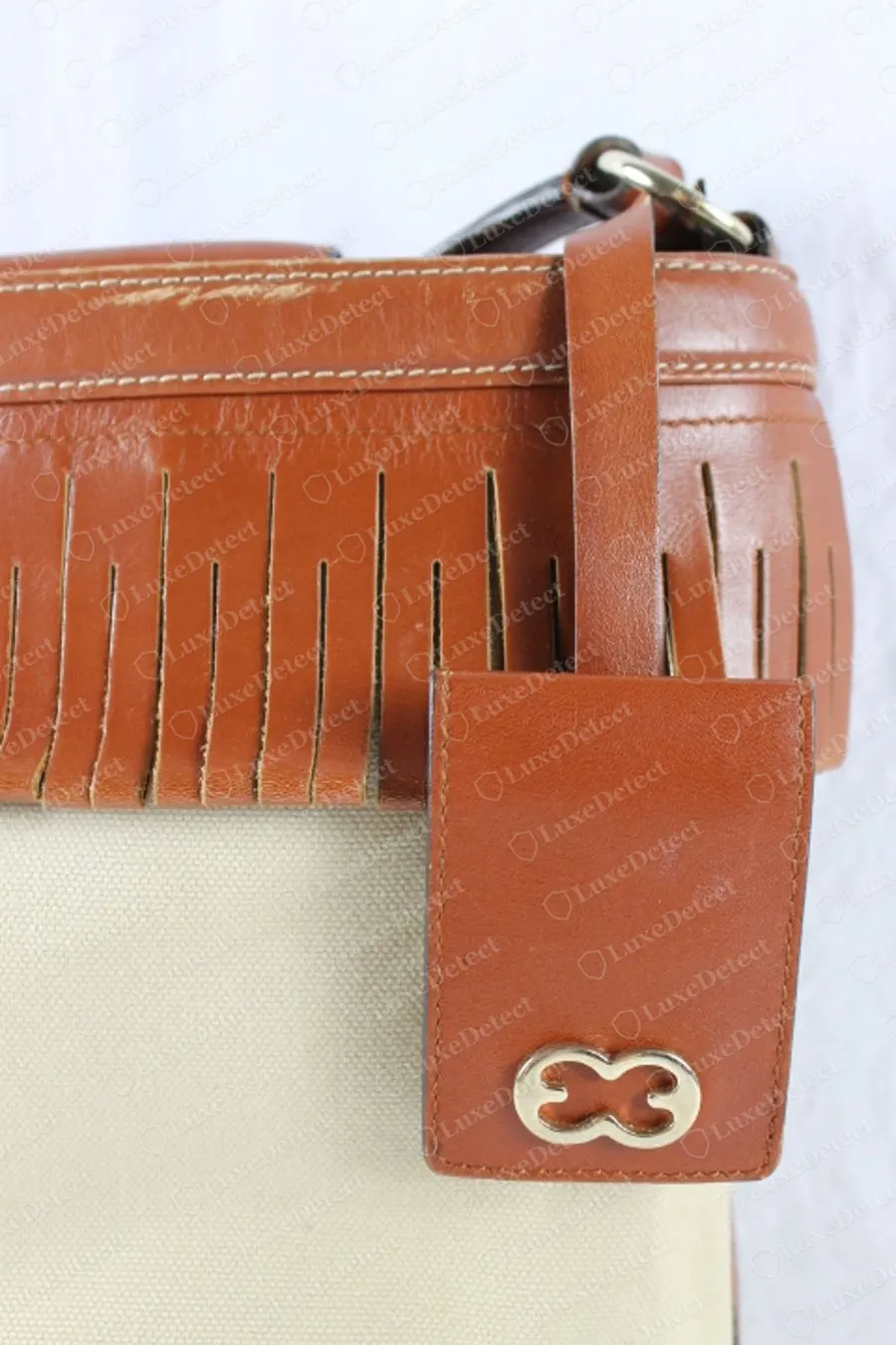 Genuine Escada leather tab on a cream canvas and tan leather shoulder bag with fringe, carrying a gold-outlined interlocking double-E logo at the bottom