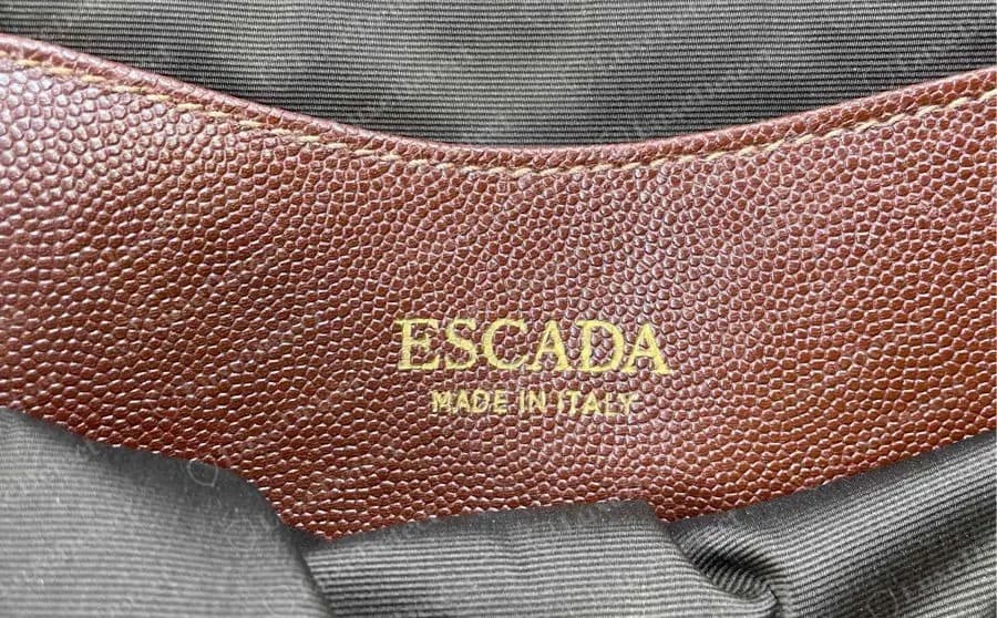 Genuine Escada interior patch of grained brown leather stamped in gold with ESCADA and MADE IN ITALY, stitched inside a bag with a dark grosgrain lining