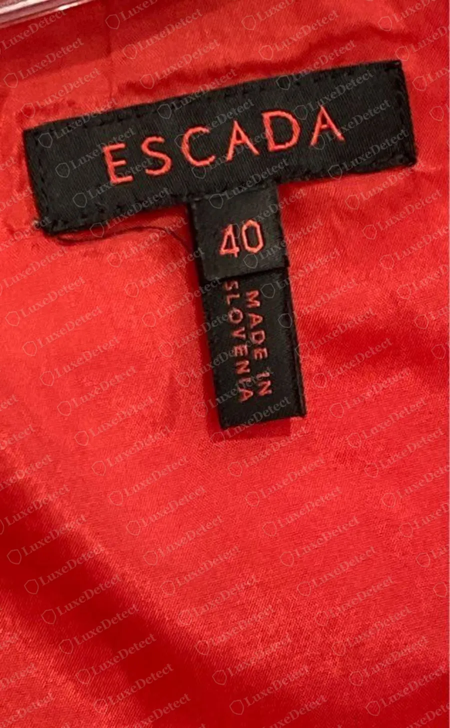 Genuine Escada black woven label with ESCADA in spaced red capitals, the size 40 beneath it and MADE IN SLOVENIA printed vertically below, sewn into a red garment