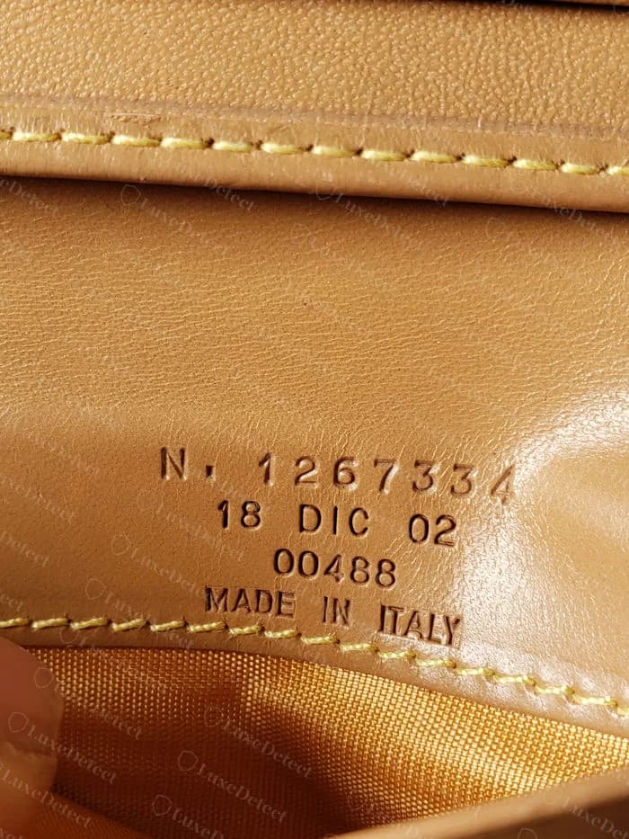 Verso de etiqueta de couro Etro original carimbado N. 1267334, 18 DIC 02, 00488 e MADE IN ITALY, no interior de uma carteira caramelo