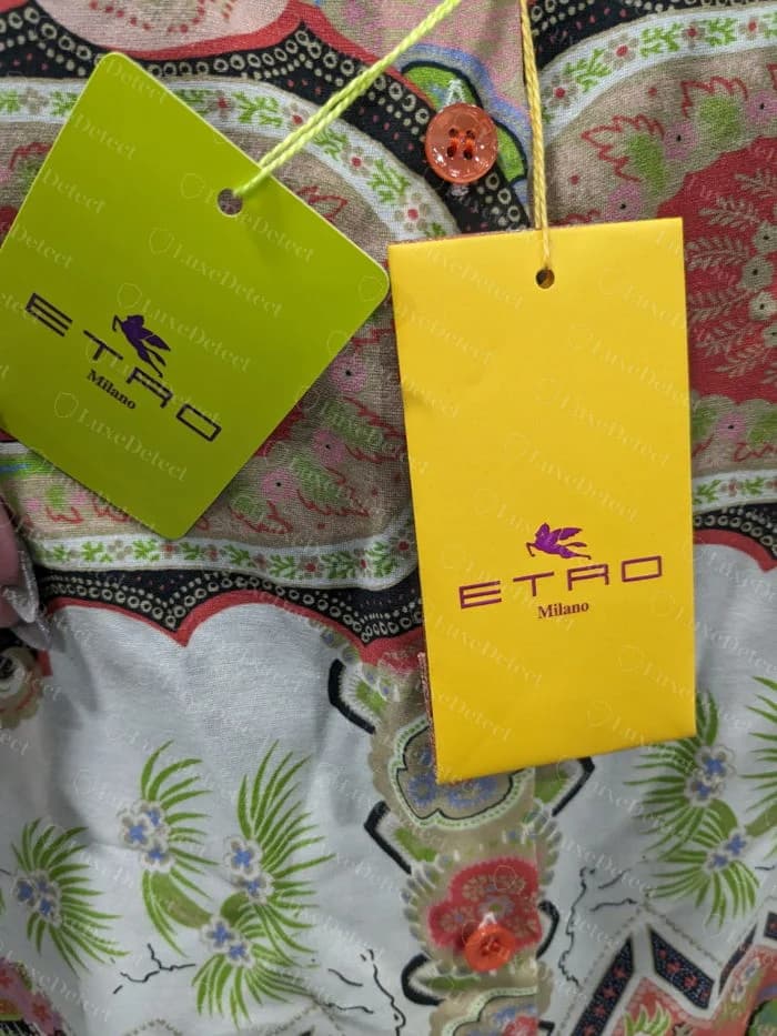 Etiquetas penduradas amarela e verde-limão Etro originais com o cavalo alado e ETRO Milano, presas por um cordão amarelo a uma blusa de algodão estampada