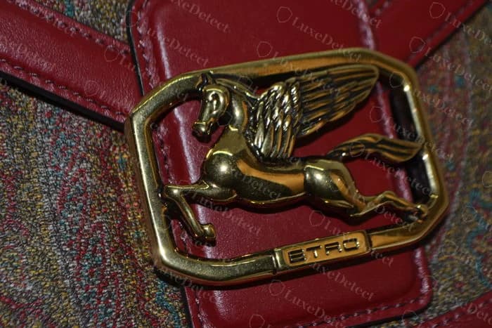 Genuine Etro gold-tone winged-horse buckle in an octagonal frame with a small ETRO plate, set on a red leather flap over paisley print